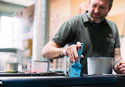 Ein Mann füllt blaue Farbe mit einem Rakel in die Druckmaschine