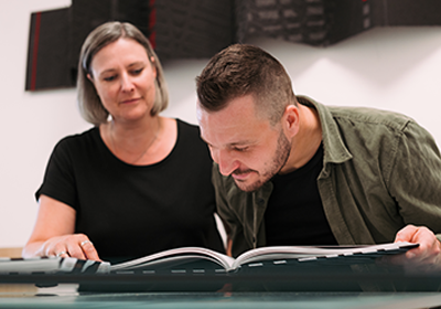 Ein Mann und eine Frau sechauen in ein gedrucktes Buch